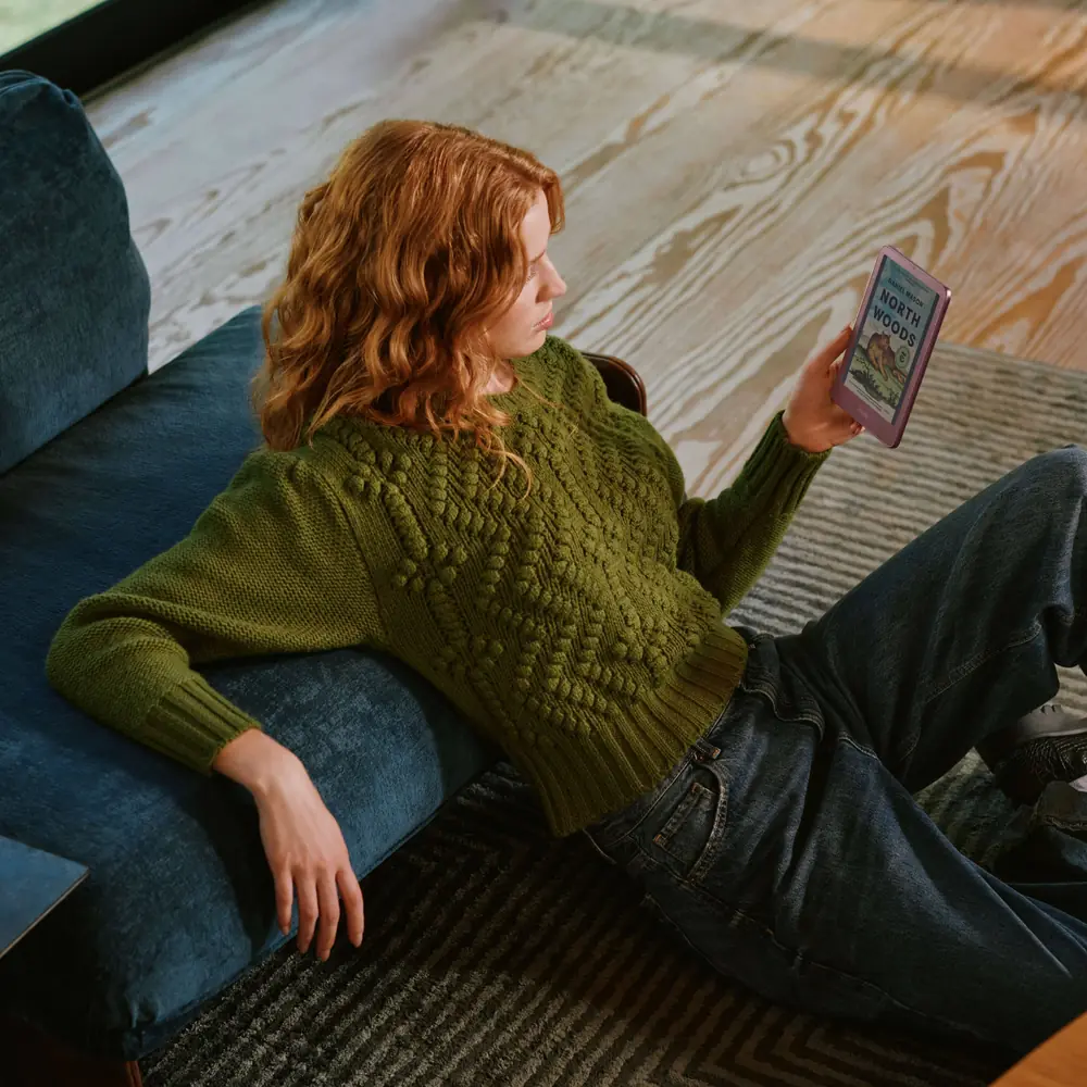 Reading on an Amazon Kindle e-reader while relaxing on a sofa