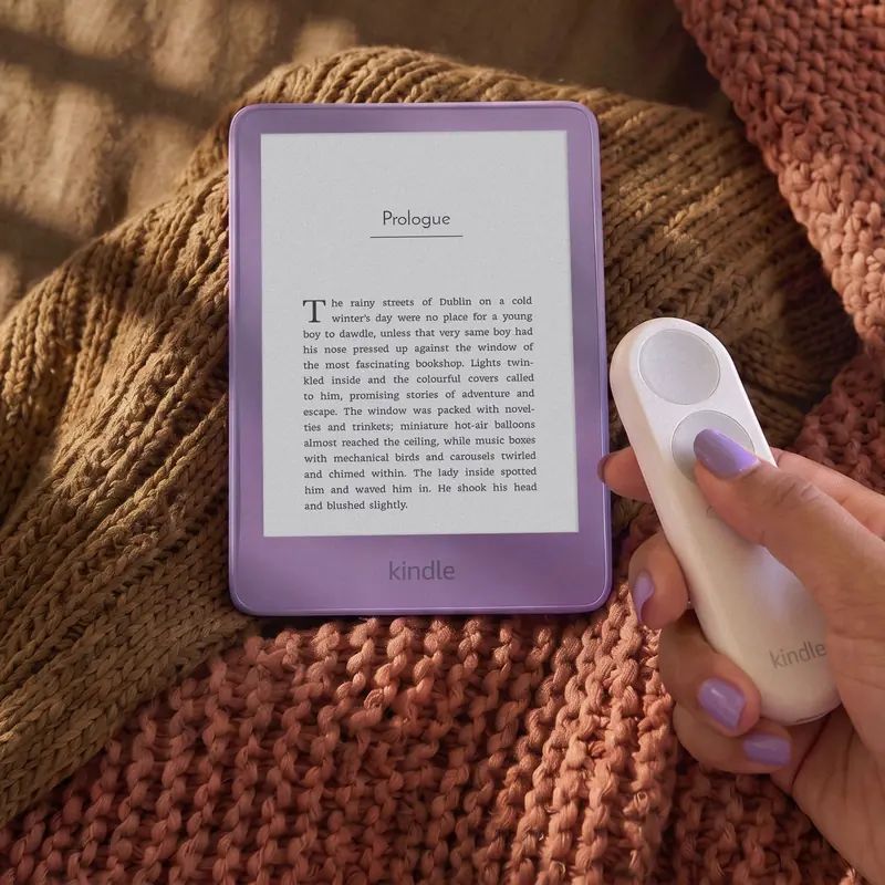 Kindle in Ube on a knit blanket next to a handheld page-turn remote
